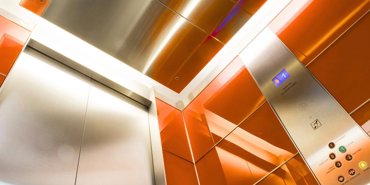 Modern sleek orange and stainless steel elevator cab interior